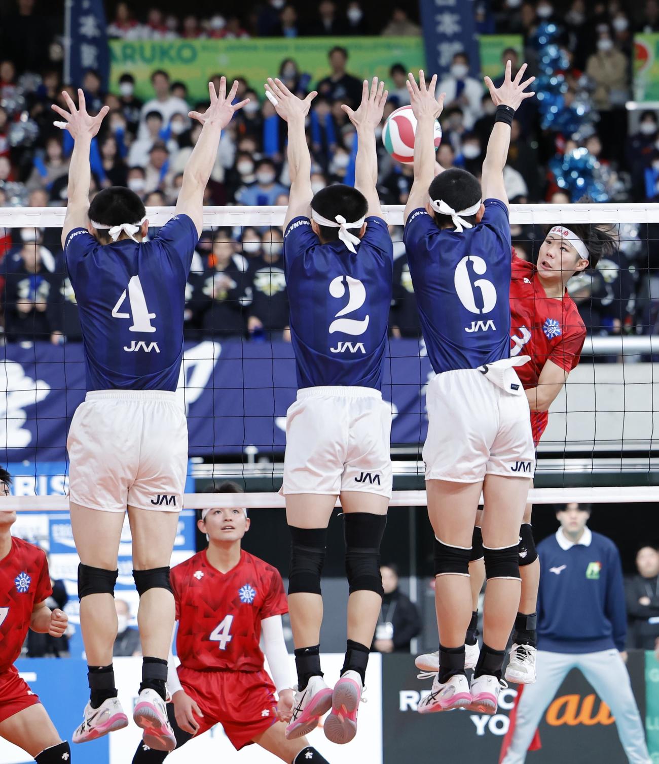 高知商対日本航空　第2セット　スパイクを放つ高知商・沢村（右）とブロックをする日本航空の選手たち（撮影・山本朝陽）