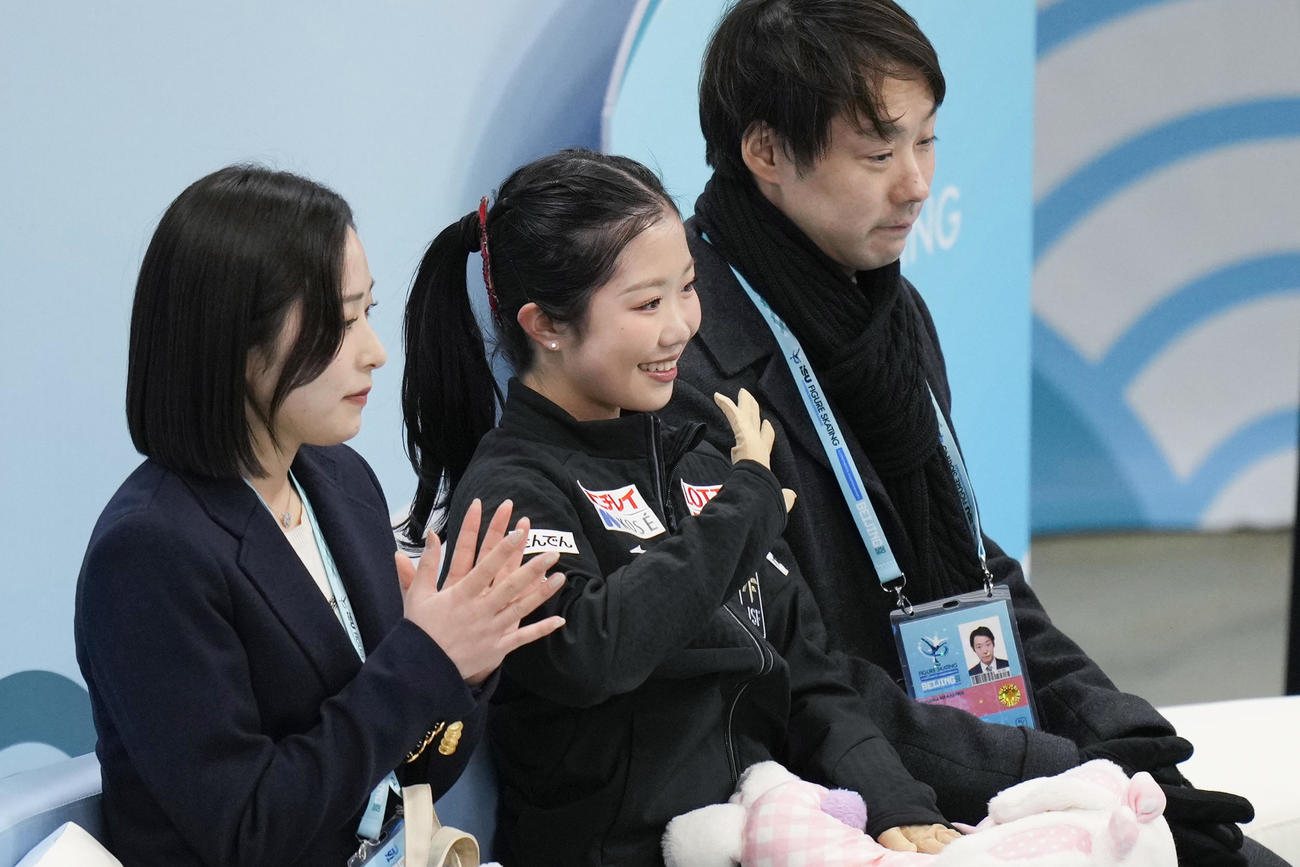 女子SPの得点を確認し、笑顔の中井亜美（中央）。奥は中庭健介コーチ＝北京（共同）