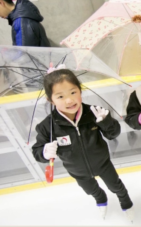 傘を手に、笑顔で写真に納まる幼少期の中井亜美