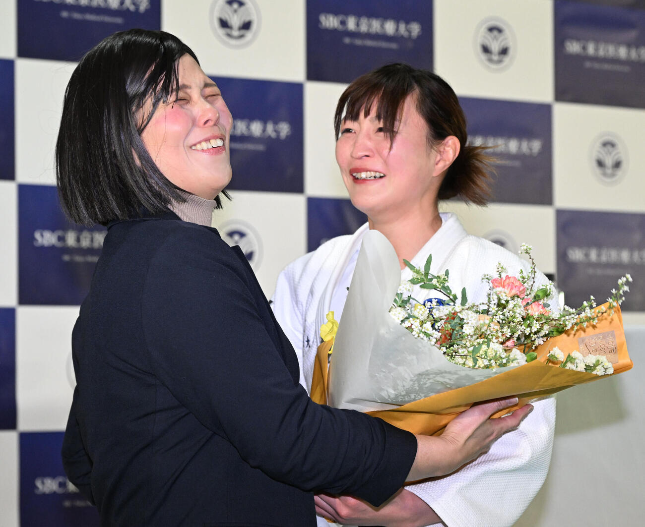 記者会見の会場にサプライズで訪れた今井コーチ（左）から花束を贈られ涙ぐむ角田夏実（撮影・千葉一成）