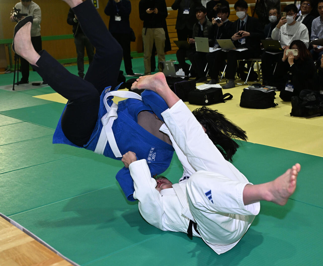 記者会見の会場にサプライズで訪れた今井コーチ（左）を巴投げする角田夏実＝2026年1月30日