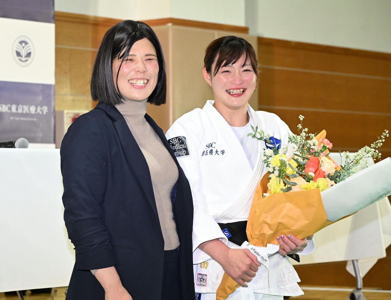 記者会見の会場にサプライズで訪れた今井コーチ（左）から花束を贈られた角田夏実（撮影・千葉一成）