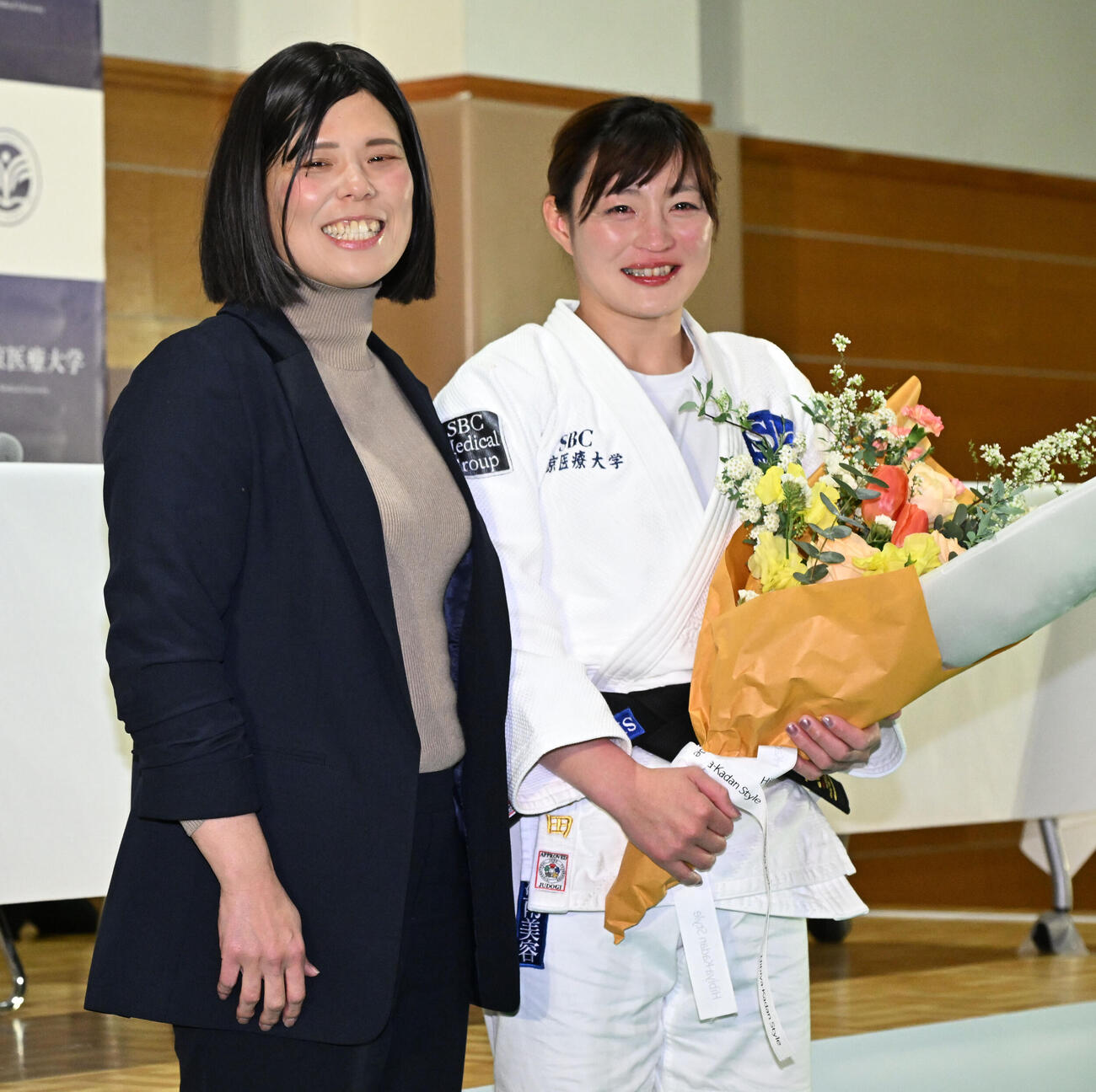 記者会見の会場にサプライズで訪れた今井コーチ（左）から花束を贈られた角田夏実（撮影・千葉一成）