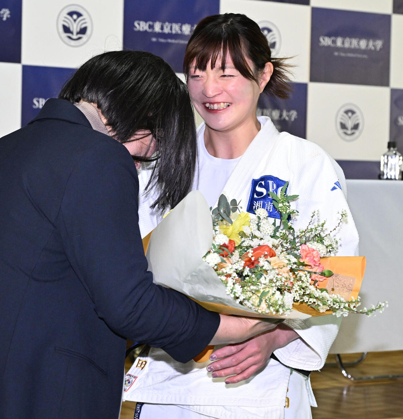 記者会見の会場にサプライズで訪れた今井コーチ（左）から花束を贈られ涙ぐむ角田夏実（撮影・千葉一成）