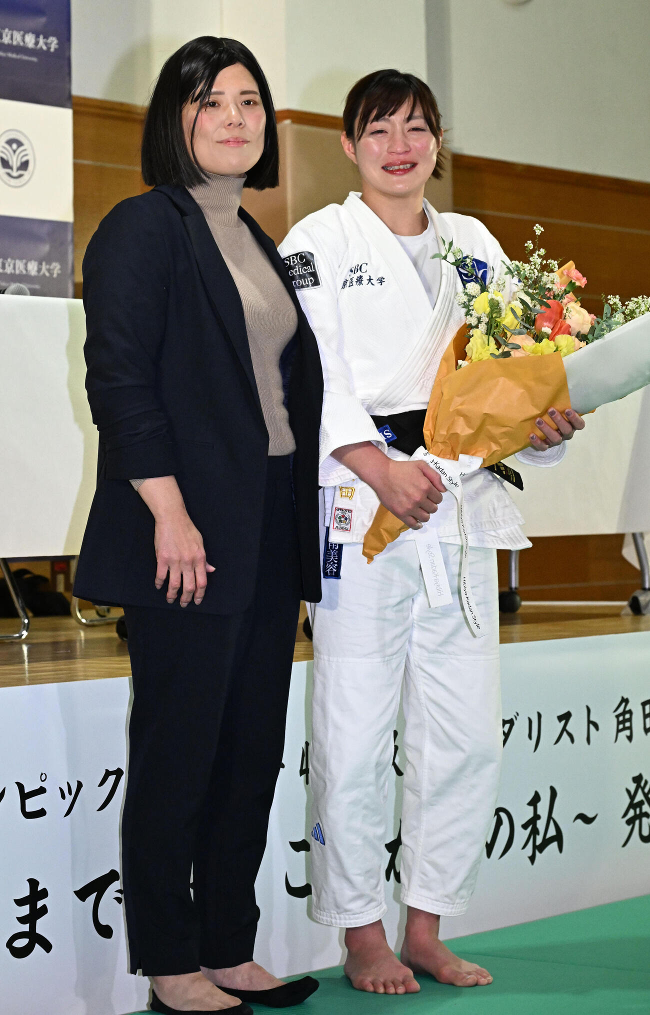 記者会見の会場にサプライズで訪れた今井コーチ（左）から花束を贈られた角田夏実（撮影・千葉一成）