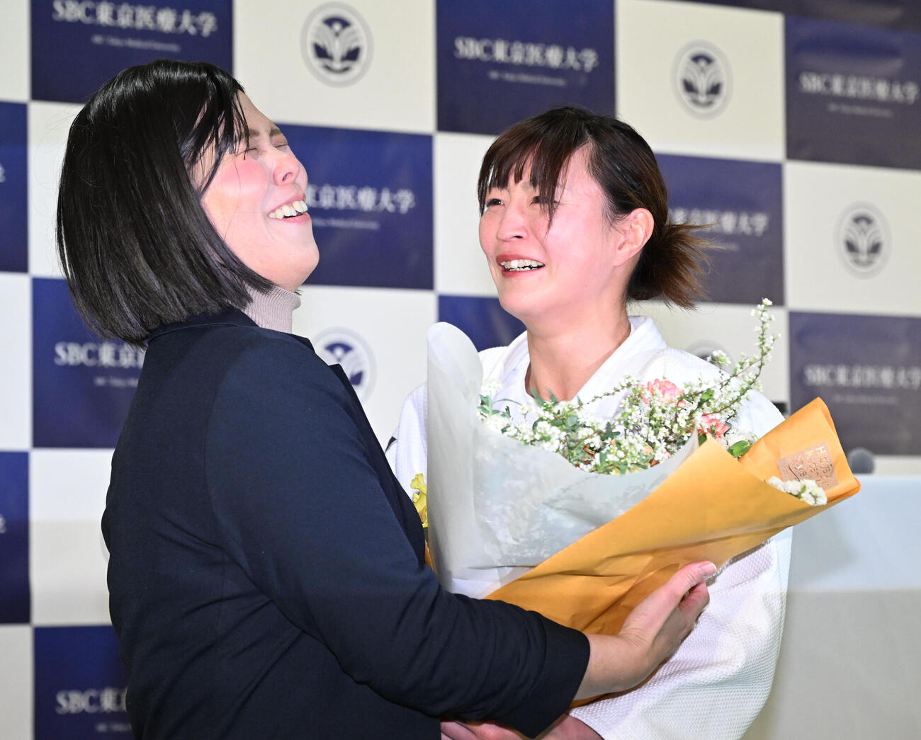 記者会見の会場にサプライズで訪れた今井コーチ（左）から花束を贈られ涙ぐむ角田（撮影・千葉一成）