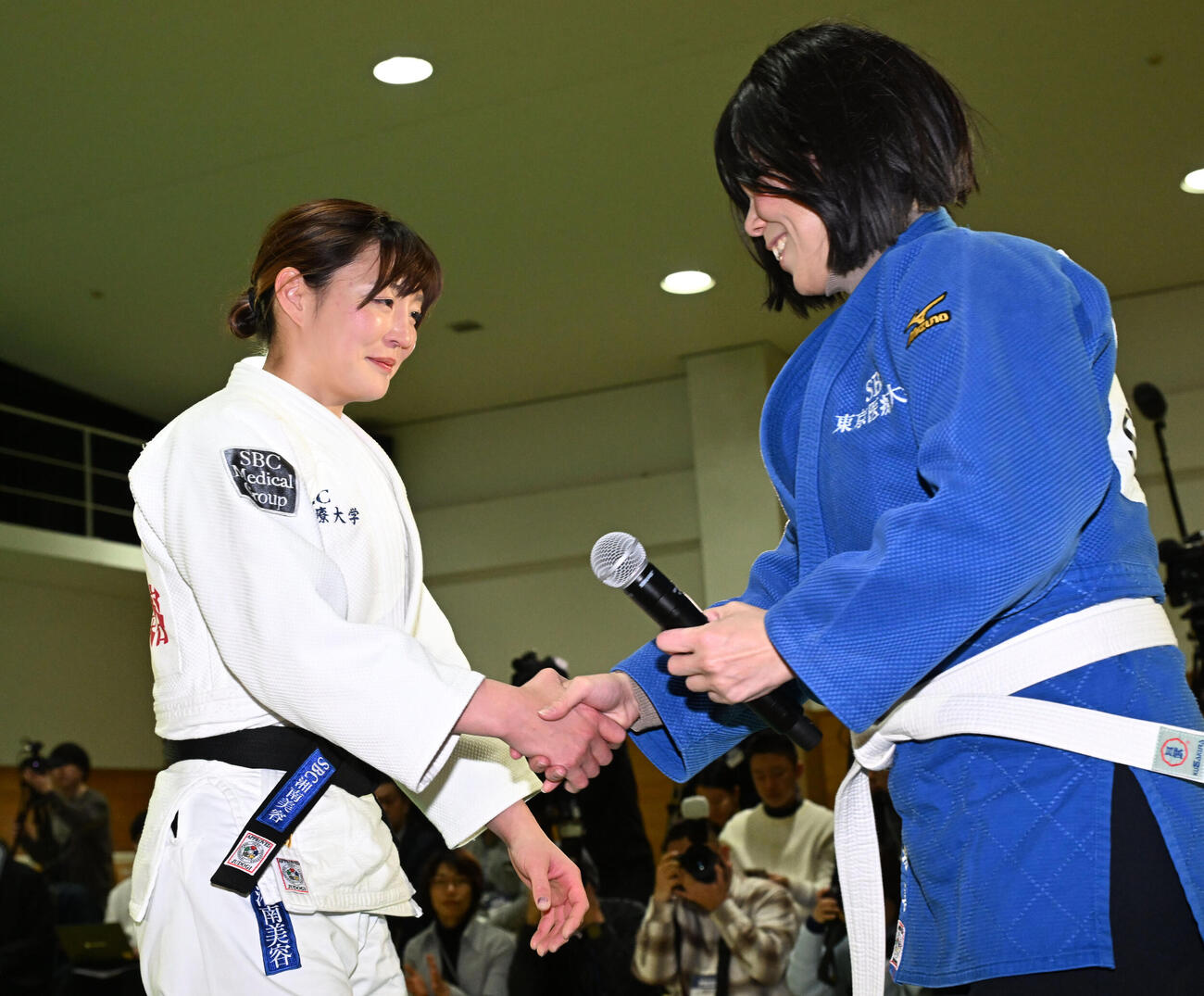 記者会見の会場にサプライズで訪れた今井コーチ（右）に巴投げをかけた後、握手する角田（撮影・千葉一成）