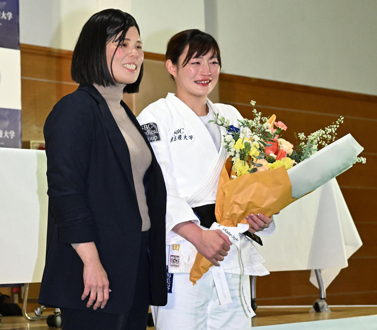 記者会見の会場にサプライズで訪れた今井コーチ（左）から花束を贈られ涙ぐむ角田（撮影・千葉一成）