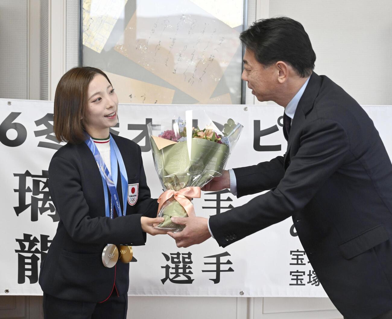兵庫県宝塚市役所で森臨太郎市長（右）から花束を受け取る「りくりゅう」ペアの三浦璃来選手（共同）