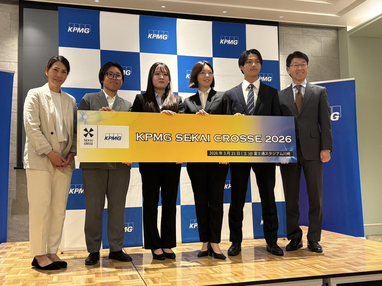 「KPMG SEKAI CROSSE 2026」の記者会見で笑顔を見せる大会代表の山田幸代氏（左）、KPMGジャパンの岡田光COO（右）、実行委員会の大学生ら
