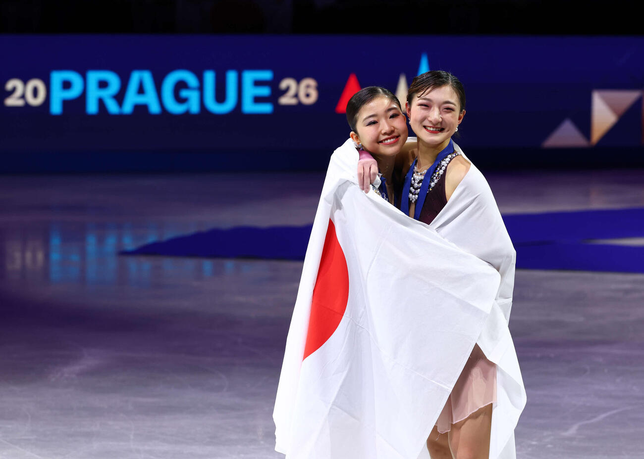 フィギュア世界選手権　今大会限りで現役引退の坂本花織（右）は総合優勝を飾り、2位の千葉百音と日の丸に包まり笑顔で記念撮影（撮影・PNP）