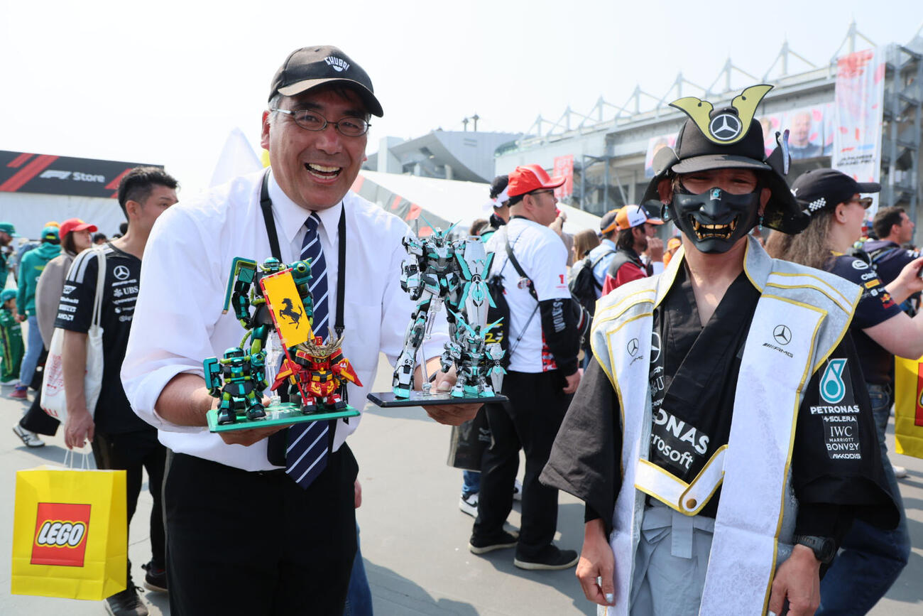 左からアストンマーティンホンダ、フェラーリ、メルセデス仕様のガンプラをアピールするファン（撮影・宮崎幸一）