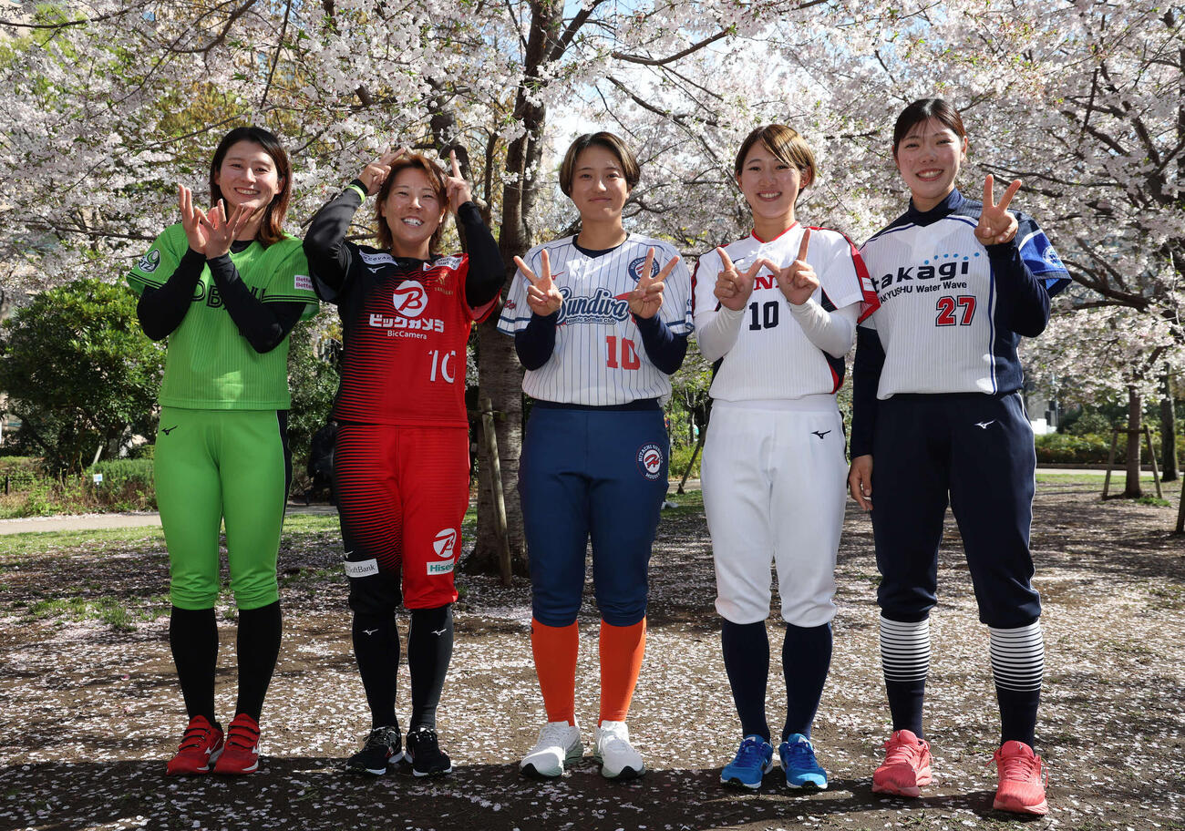 桜の下でポーズを決めるソフトボール女子JDリーグの、左から伊予銀行の辻井美波さん、ビックカメラ高崎の内藤実穂さん、日立の笠原朱里さん、ホンダの大川茉由さん、タカギ北九州の鹿野愛音さん（撮影・丹羽敏通）