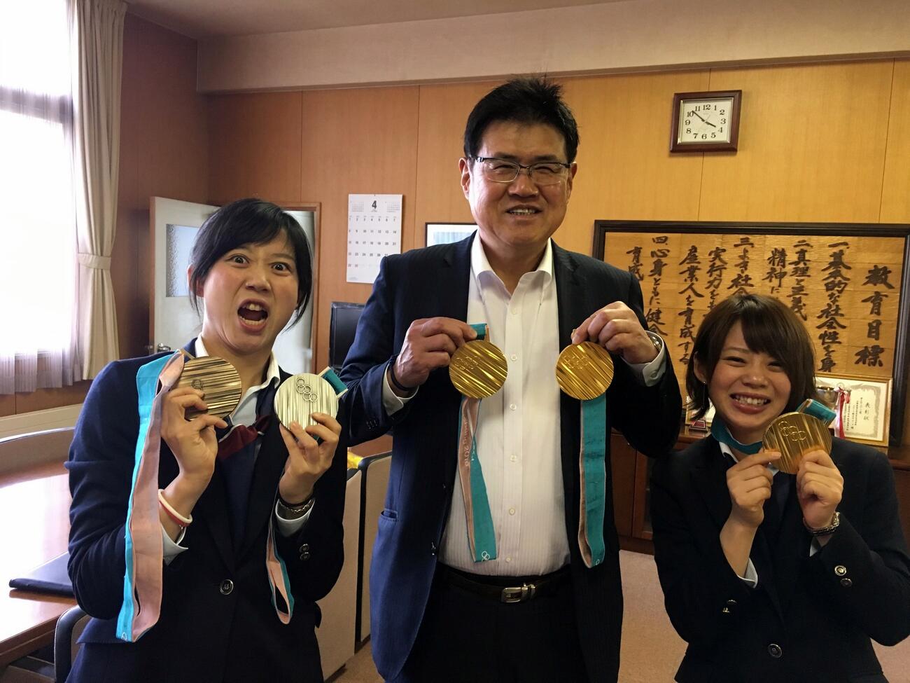 18年平昌五輪で取ったメダルを帯広南商高時代の東出俊一監督に渡し、記念撮影する左から高木美、東出さん、高木菜（2022年2月撮影）