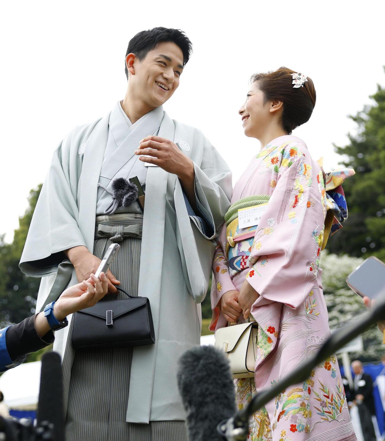 春の園遊会で報道陣の取材に応じるミラノ・コルティナ冬季五輪フィギュアスケート・ペアの金メダリストで「りくりゅう」の三浦璃来（右）と木原龍一（共同）