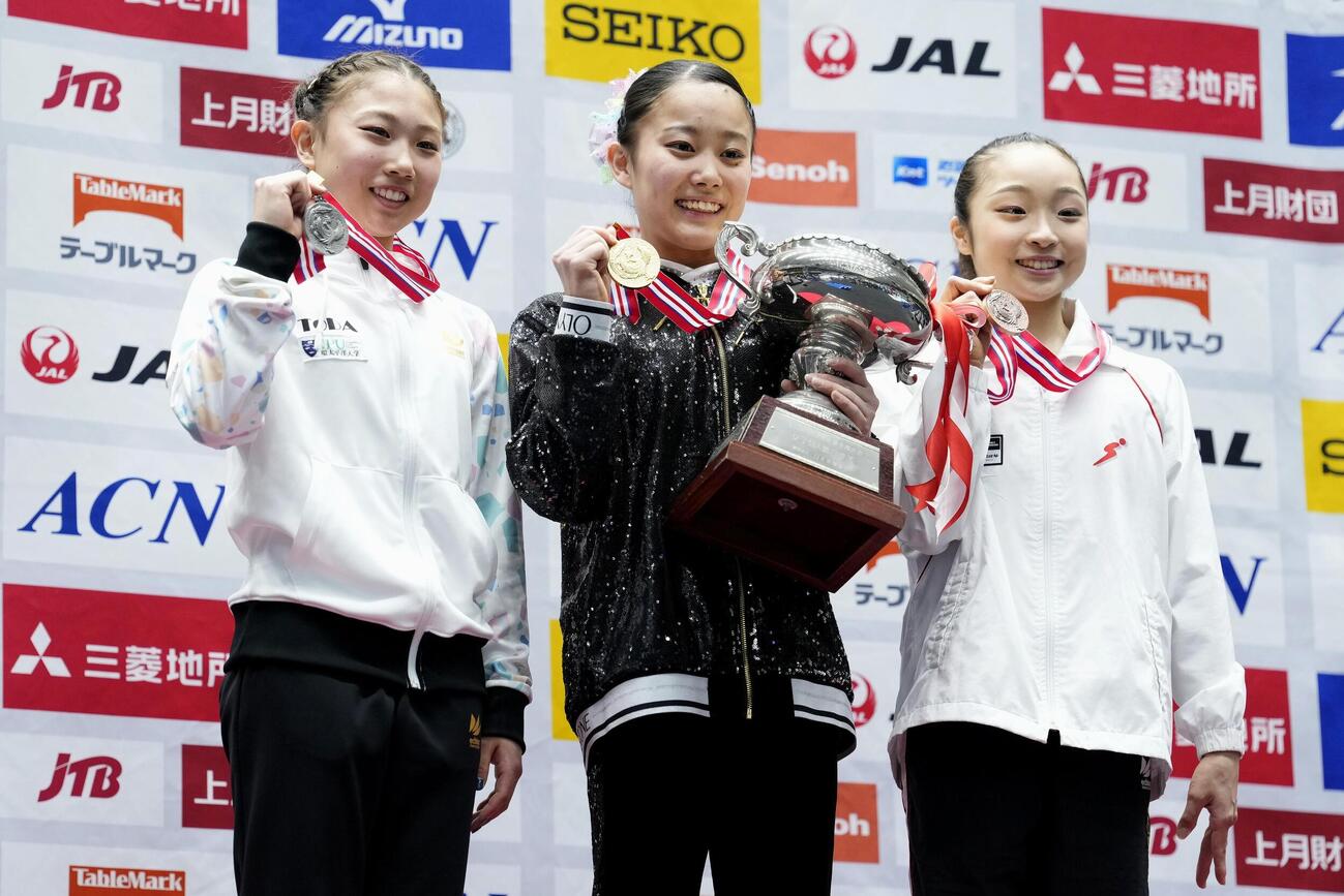 女子個人総合で初優勝した西山実沙（中央）。左は2位の岸里奈、右は3位の岡村真（共同）
