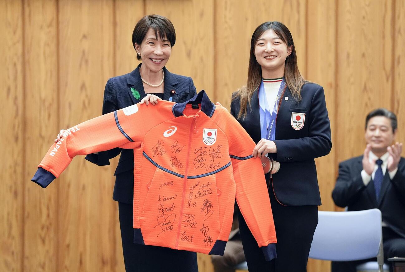 フィギュアスケート女子の坂本花織（右）からサイン入りのウエアを贈られ笑顔の高市首相（共同）