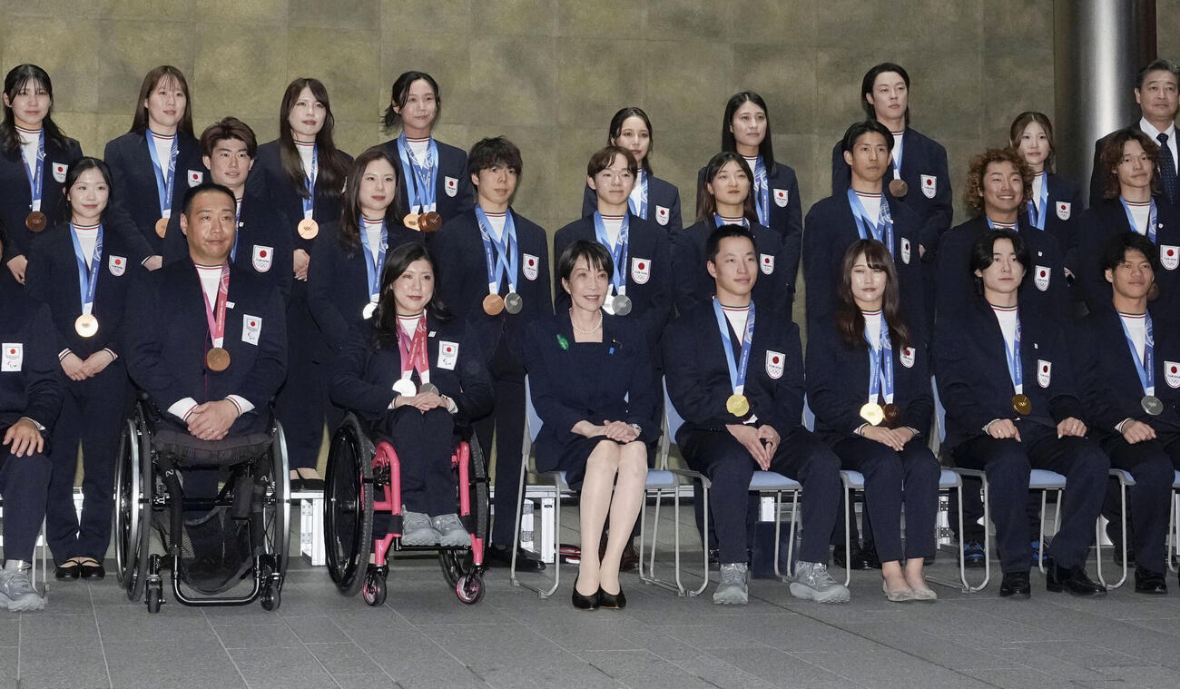 高市首相（中央）と写真に納まるミラノ・コルティナ冬季五輪・パラリンピックの日本選手団＝24日午後、首相官邸（共同）