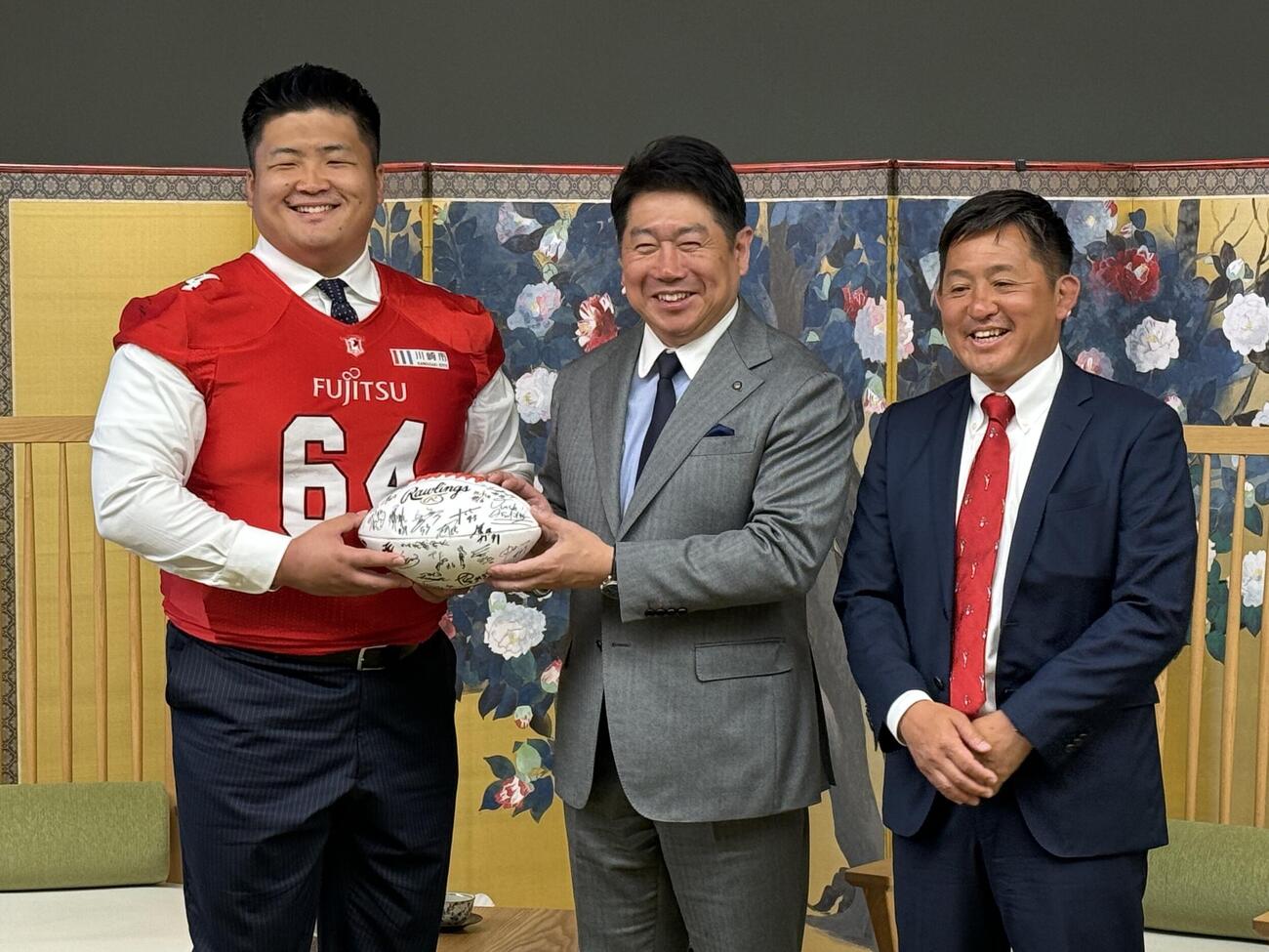 集合写真に収まった、左から順に富士通の大久保壮哉、川崎市の福田紀彦市長、山本洋ヘッドコーチ（富士通提供）