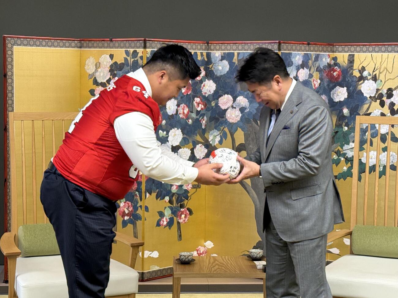 ボールを手渡す富士通の大久保壮哉（左）と川崎市の福田紀彦市長（富士通提供）