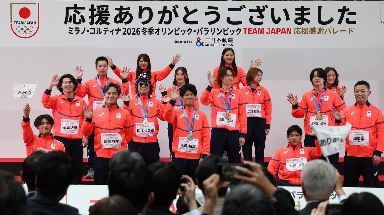 手を振って写真二納まる戸塚優斗らスノーボードチームとパラアイスホッケーチーム（撮影・丹羽敏通）