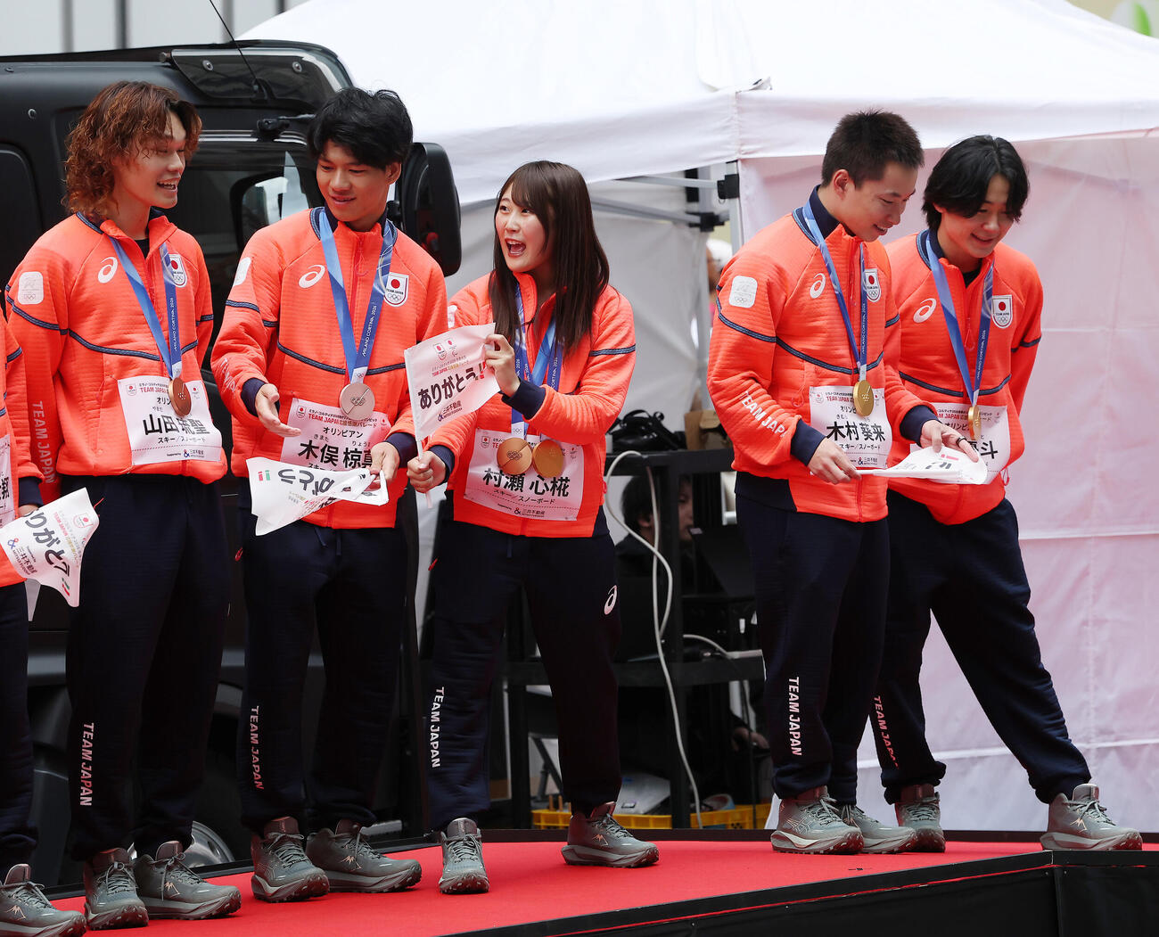 ステージで笑顔を見せる村瀬心椛（中央）らスノーボードの選手たち（撮影・河田真司）