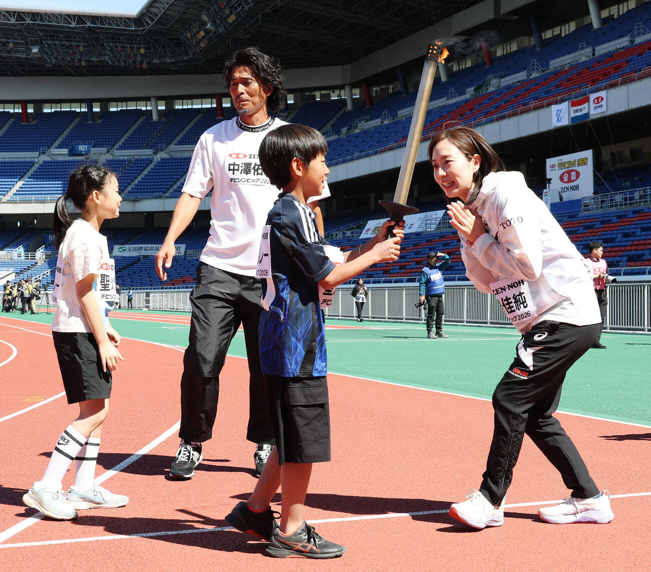 JA全農杯チビリンピック2026　子どもたちと聖火リレーする中沢佑二さん（左）と石川佳純さんと（撮影・宮地輝）