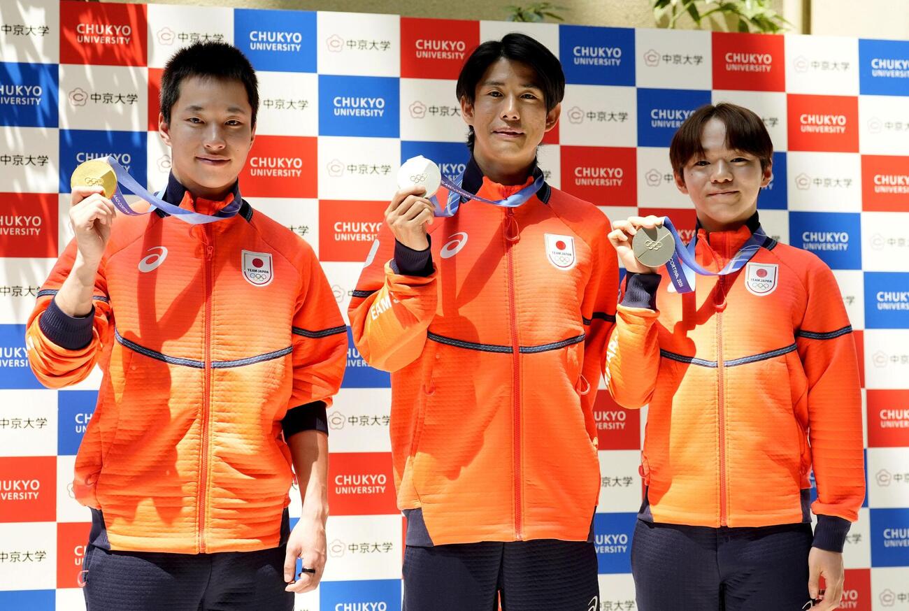 中京大で開かれたミラノ五輪報告会で、メダルを手にポーズをとる（左から）木村葵来、堀島行真、鍵山優真＝15日、名古屋市（共同）