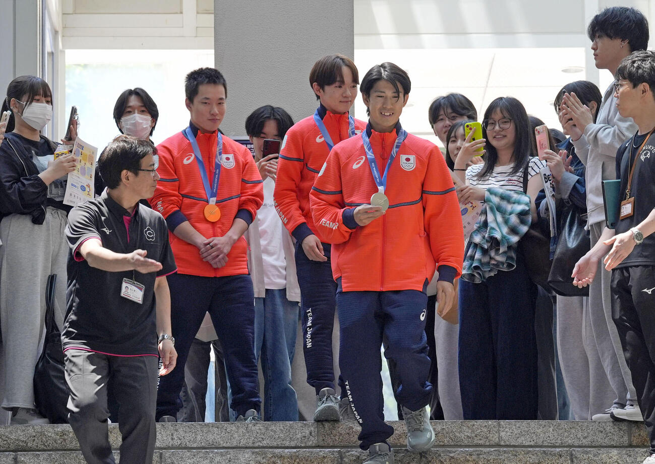 中京大で開かれたミラノ五輪報告会で、学生らに迎えられる（右から）堀島行真、鍵山優真、木村葵来＝15日、名古屋市（共同）
