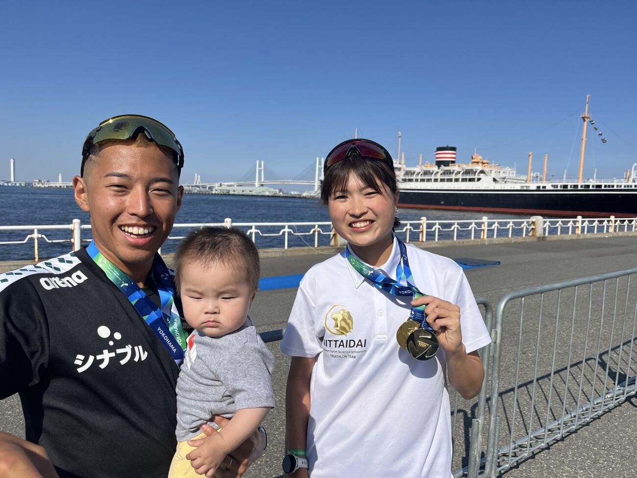 氷川丸をバックに優勝メダルを掲げる橋本悠輝（左）と島崎茉央（右）