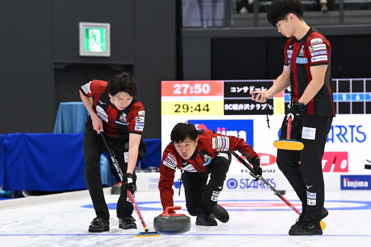 ストーンを投じるコンサドーレ阿部晋也（中央)。左は中原亜星、右は大内遥斗（C）JCA（H.IDE）