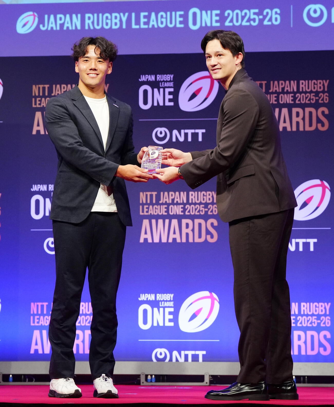 ラグビー・リーグワンの表彰式で、新人賞に選ばれ、プレゼンターを務める男子バスケットボールのテーブス海（右）と写真に納まる神戸上ノ坊駿介（撮影・江口和貴）