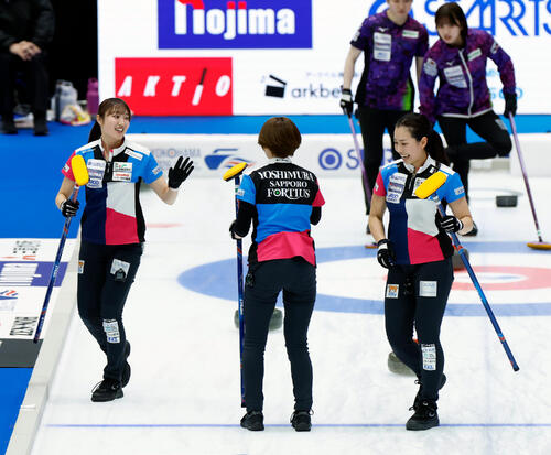 日本カーリング選手権大会 横浜2026 女子準決勝 フォルティウス対北海道銀行 第6エンド、ハイタッチをするフォルティウスの選手たち、左から小林未奈、吉村紗也香、近江谷杏菜(撮影・山本朝陽)=2026年6月13日