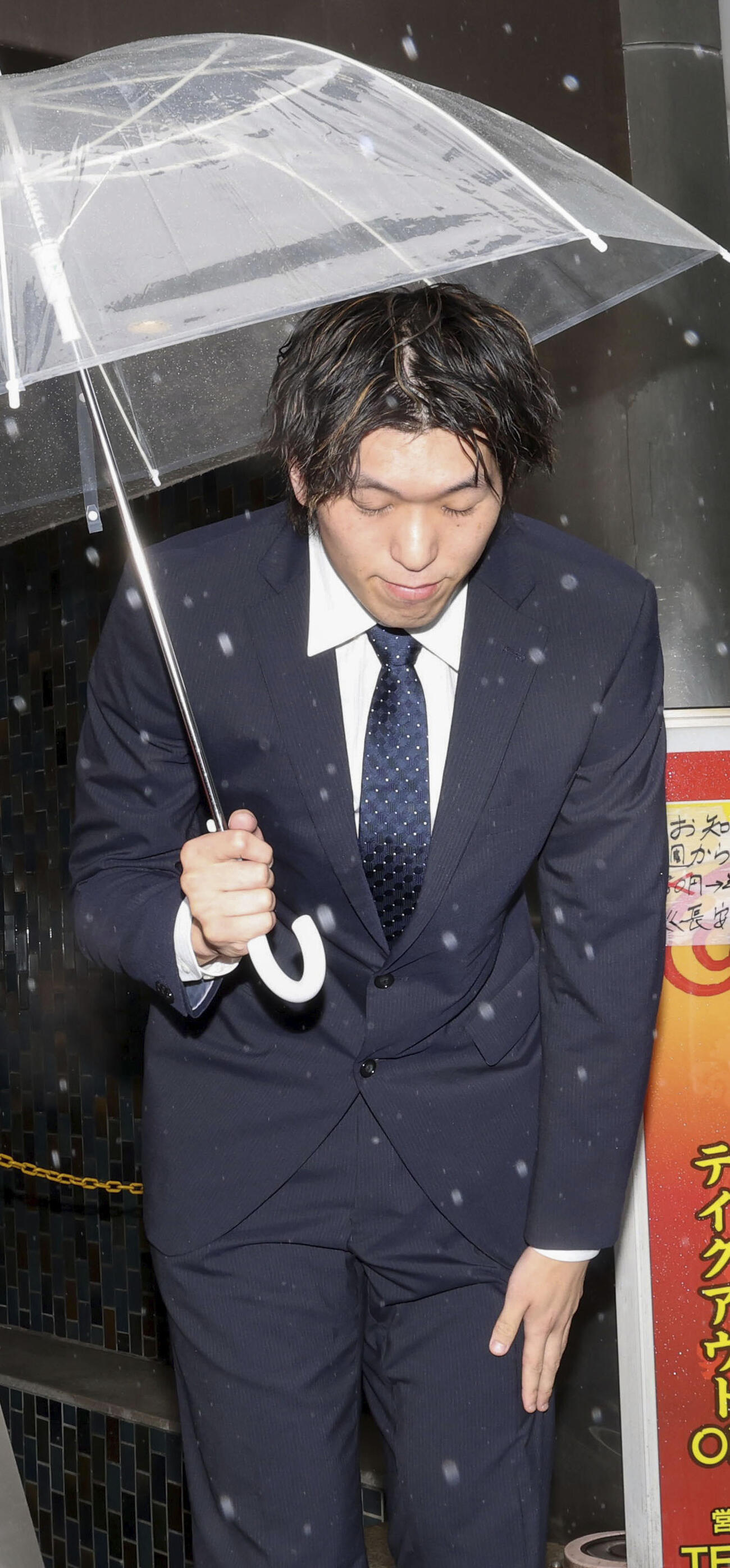 保釈され、頭を下げるバレーボール元日本代表の佐藤駿一郎被告＝18日午前、東京都港区（共同）