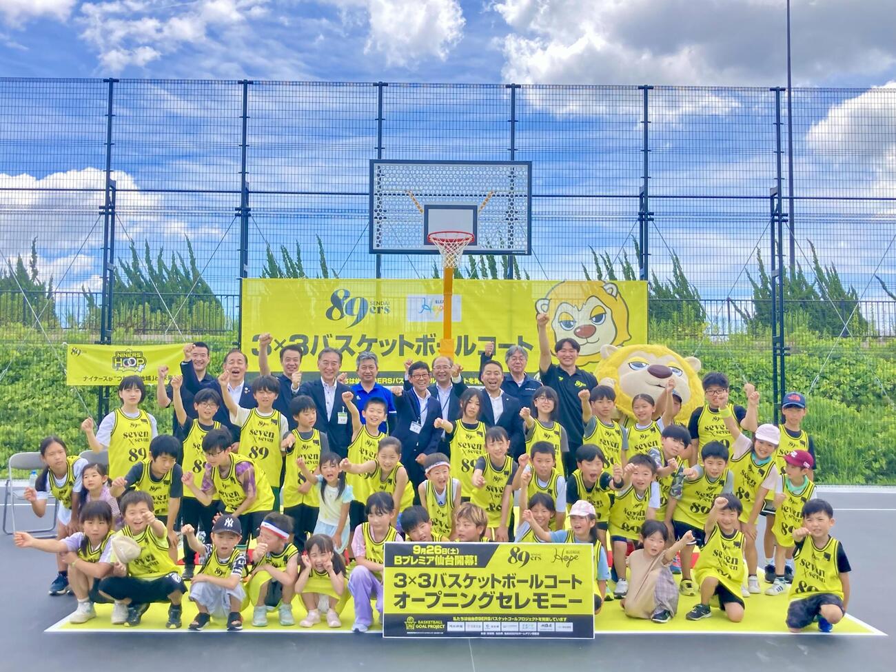 オープニングセレモニーで記念写真に納まるBプレミア仙台志村雄彦社長、阿部真冴橙、来賓とバスケ体験会に参加した児童たち（撮影・高橋香奈）