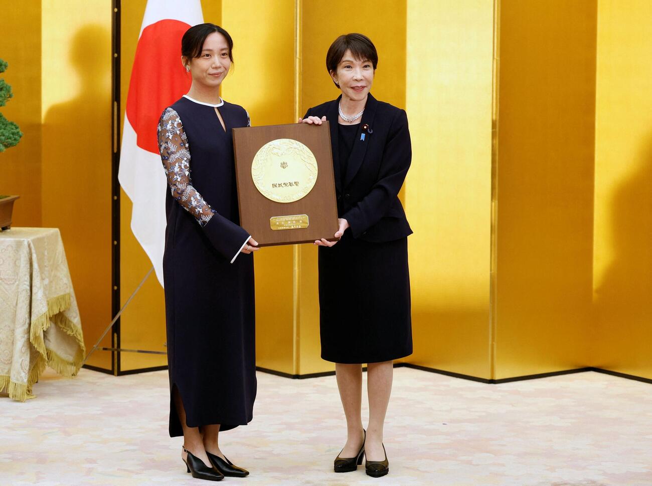 国民栄誉賞表彰式で、高市首相（右）から盾を受け取るスピードスケートの高木美帆さん（ロイター）