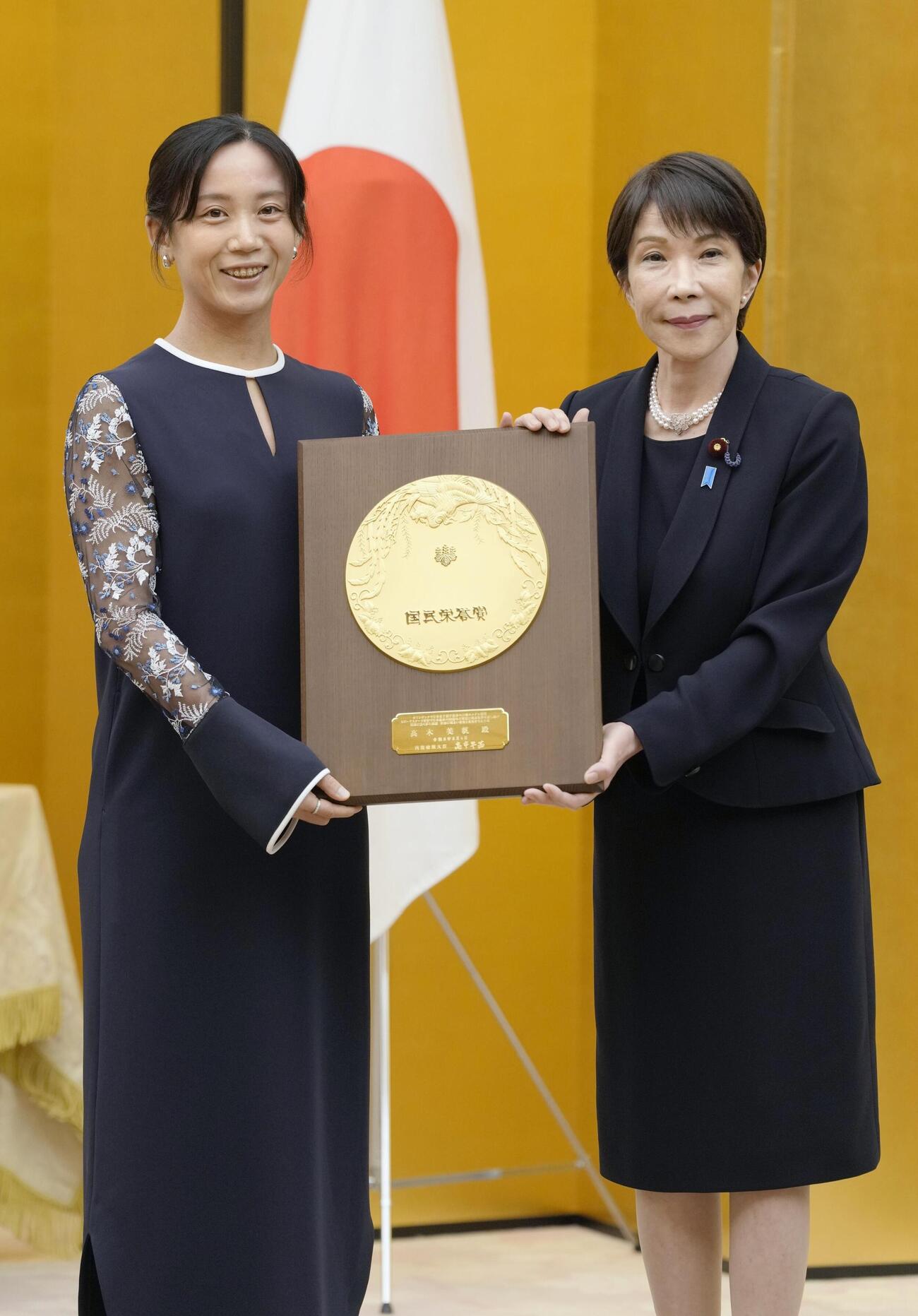国民栄誉賞表彰式で、高市首相（右）から盾を受け取るスピードスケートの高木美帆さん（共同）