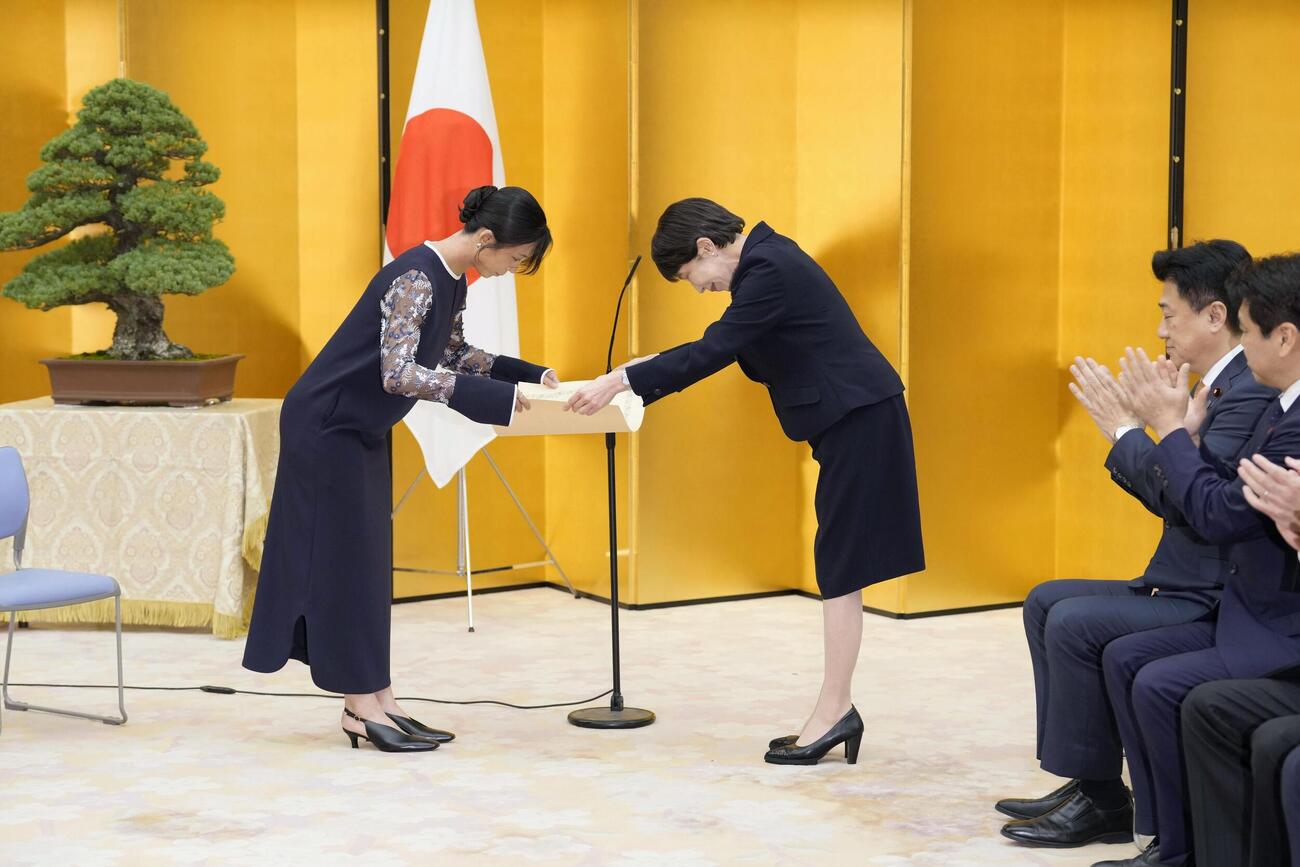国民栄誉賞表彰式で、高市首相（左から2人目）から賞状を受け取るスピードスケートの高木美帆さん（共同）
