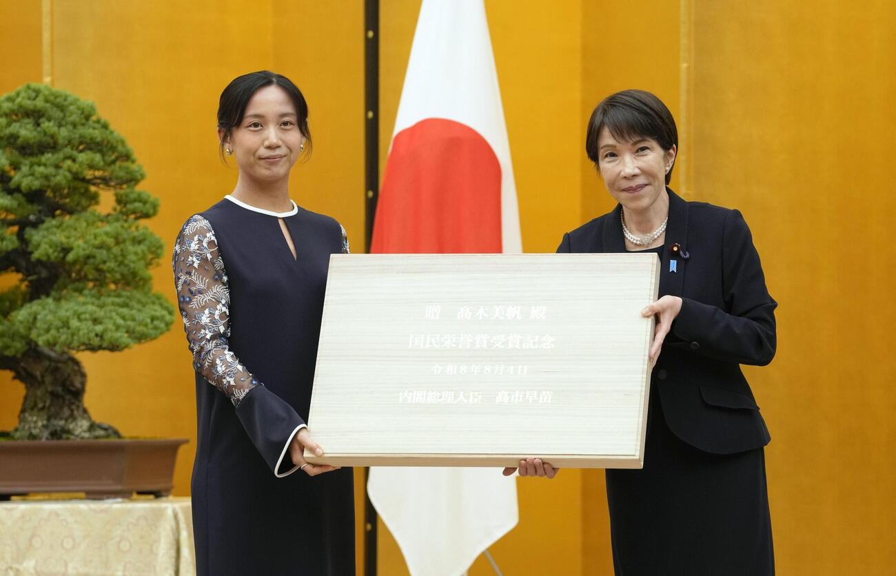 国民栄誉賞表彰式で、高市首相（右）から記念品を受け取るスピードスケートの高木美帆さん（共同）