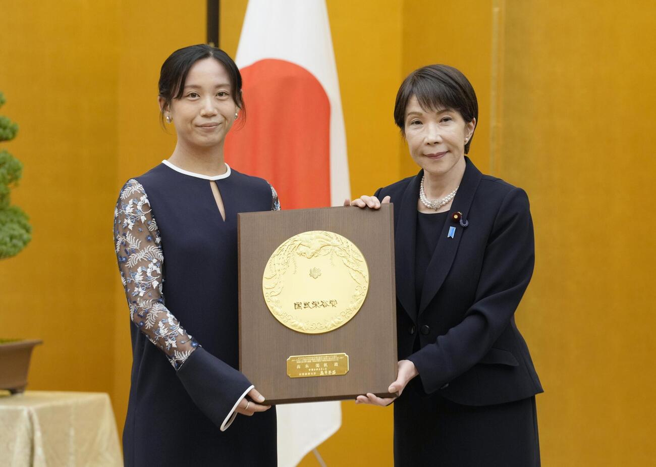 国民栄誉賞表彰式で、高市首相（右）から盾を受け取るスピードスケートの高木美帆さん（共同）