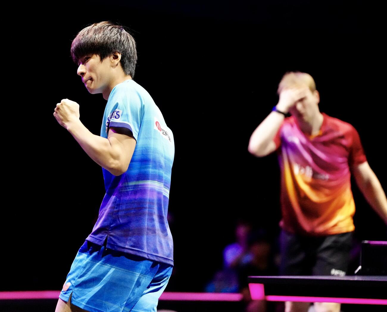 男子シングルス1回戦　第1ゲーム、ドイツのドゥダ（後方）からポイントを奪い、ガッツポーズの戸上隼輔（撮影・江口和貴）