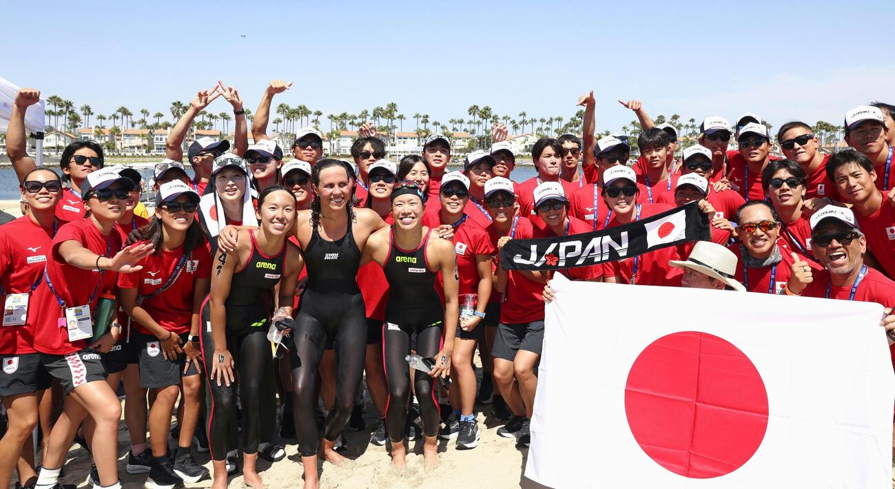 女子10キロで2位となり、競泳日本代表の選手たちと記念撮影に納まる蝦名愛梨（前列左から5人目）と3位の梶本一花（同3人目）＝ロングビーチ（共同）