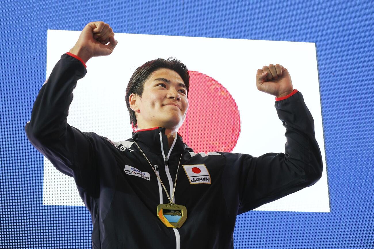 男子400メートル個人メドレーで4分6秒75をマークして優勝し、表彰式でガッツポーズする松下知之＝アーバイン（共同）