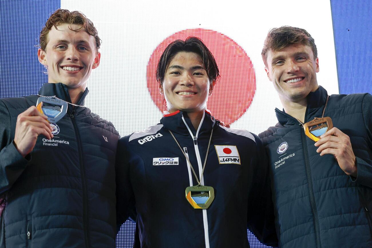 男子400メートル個人メドレーで優勝し、表彰式で笑顔を見せる松下知之（中央）＝アーバイン（共同）