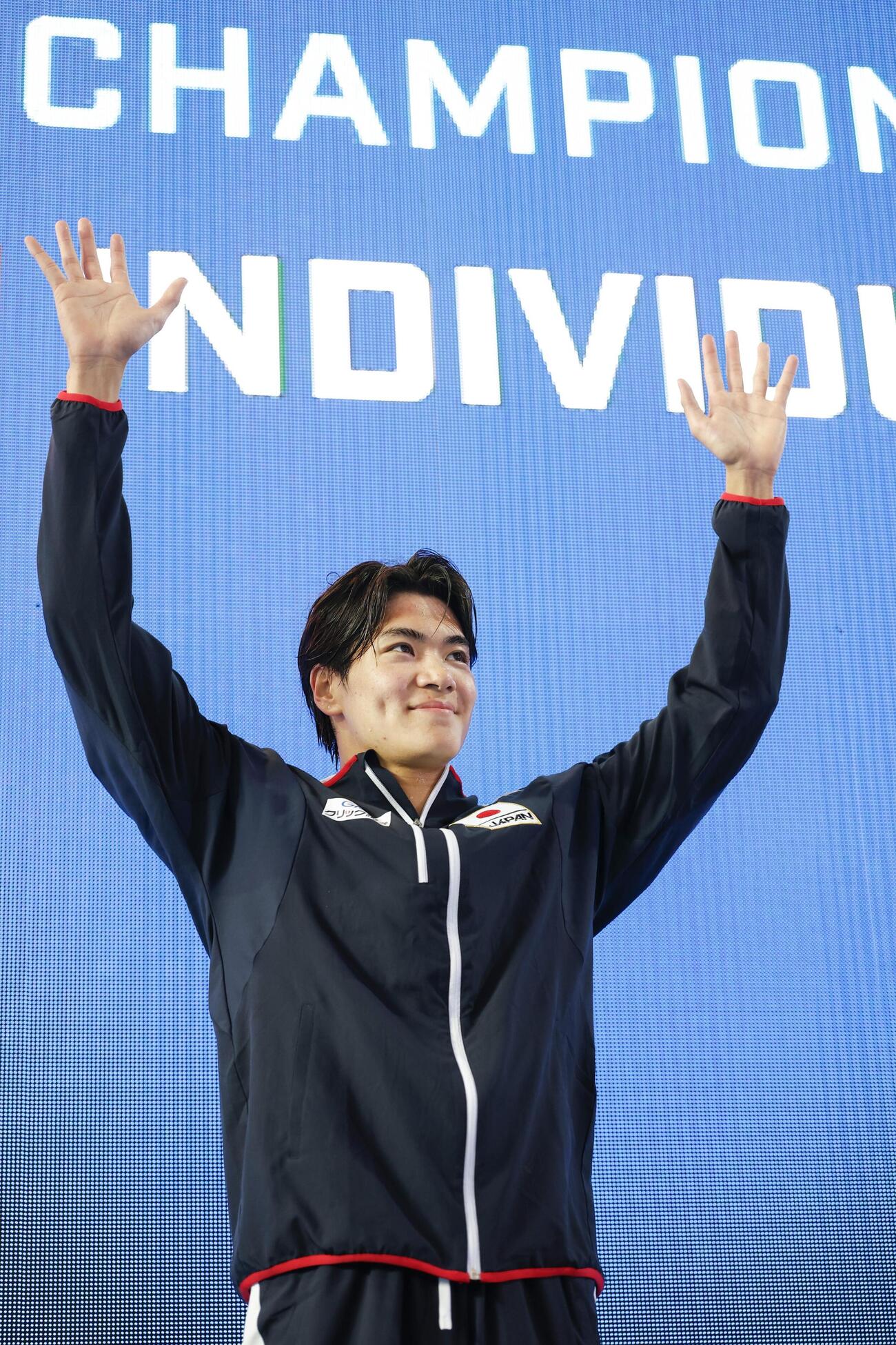男子400メートル個人メドレーで優勝し、表彰式で声援に応える松下知之＝アーバイン（共同）