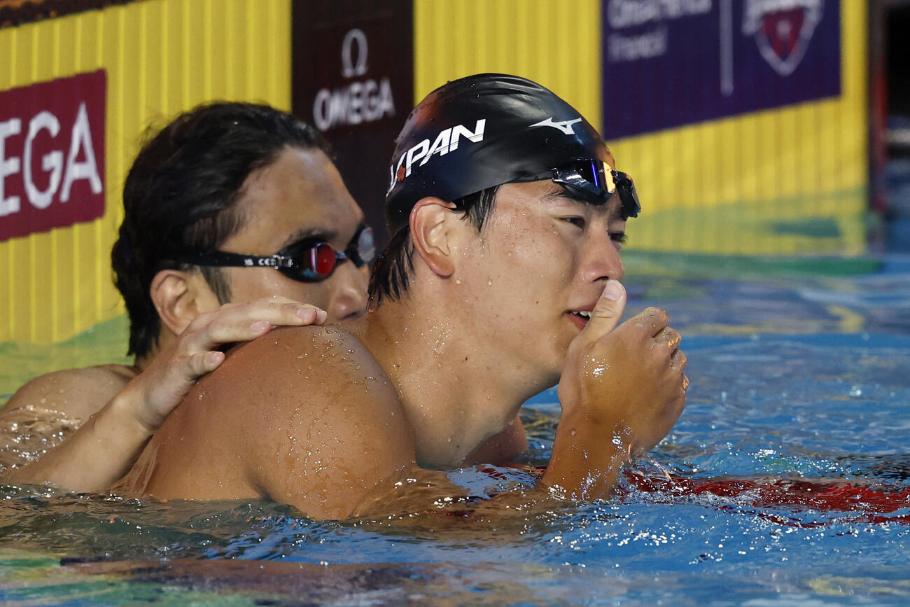 男子100メートルバタフライ決勝のレースを終え、松元克央（奥）に健闘をたたえられる4位となった光永翔音＝アーバイン（共同）