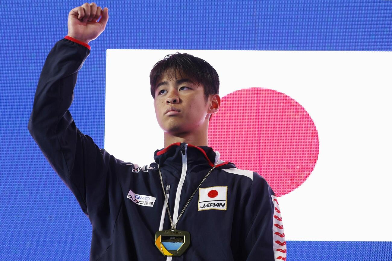 男子200メートル背泳ぎで優勝し、表彰式でガッツポーズする小島夢貴＝アーバイン（共同）