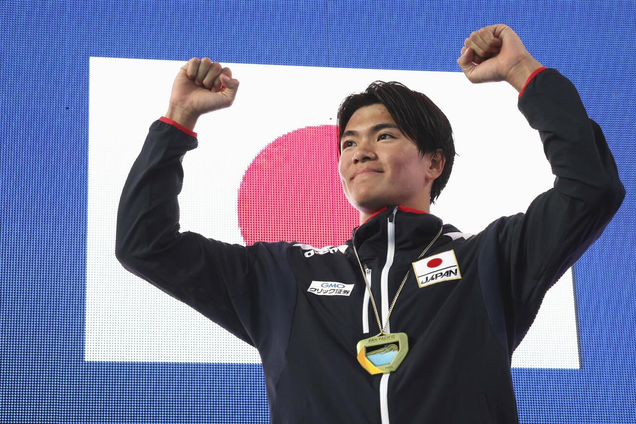 男子200メートル個人メドレーで優勝し、表彰式でガッツポーズする松下知之（共同）