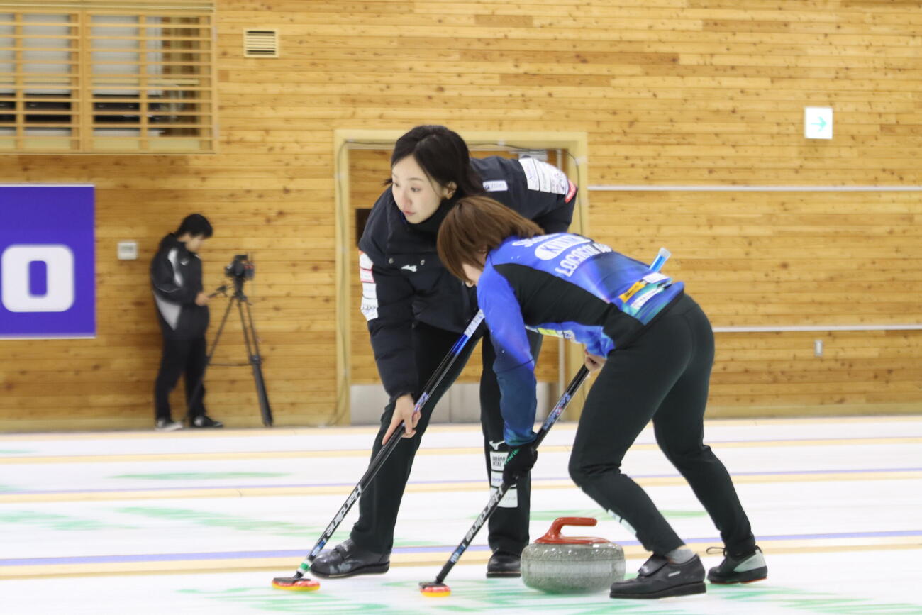 投げた後すぐスイープに加わるロコ・ソラーレ藤沢五月。右は鈴木夕湖