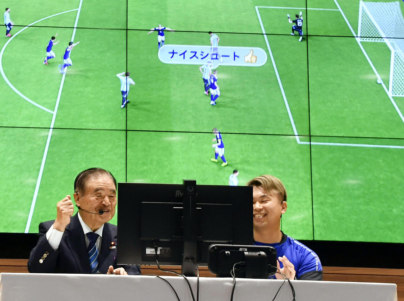 サッカーゲームの「eフットボール」を体験する日本スポーツ協会の遠藤利明会長（左）（共同）